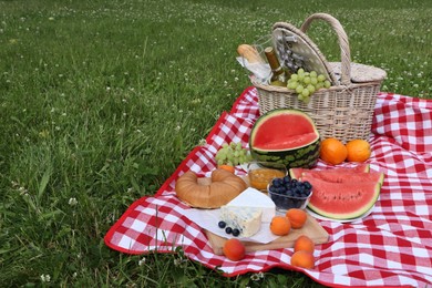 Picnic blanket with delicious food and wine outdoors on summer day, space for text