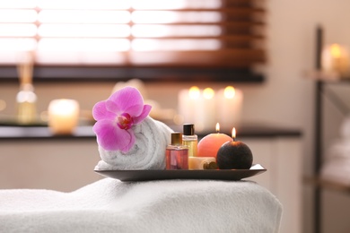 Photo of Composition with towel, candles and oils on massage table in spa salon