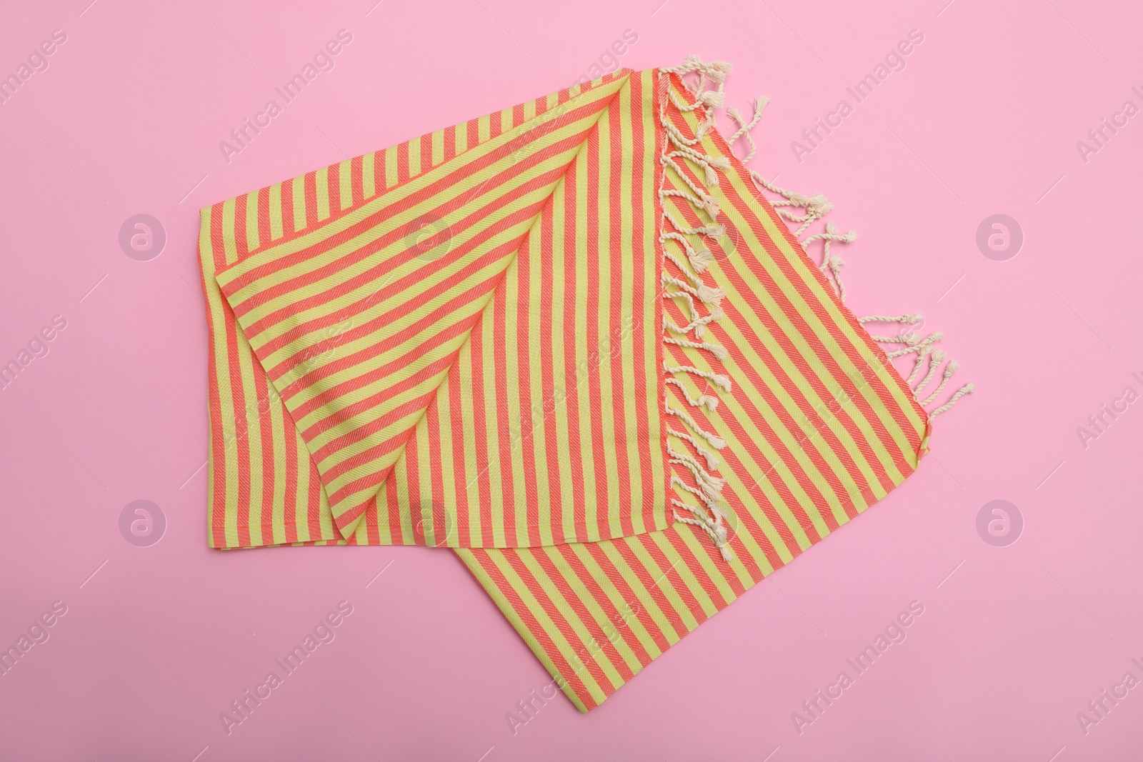 Photo of Folded striped beach towel on pink background, top view