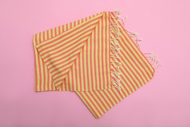 Folded striped beach towel on pink background, top view