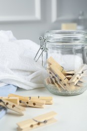 Many wooden clothespins and garments on white table indoors