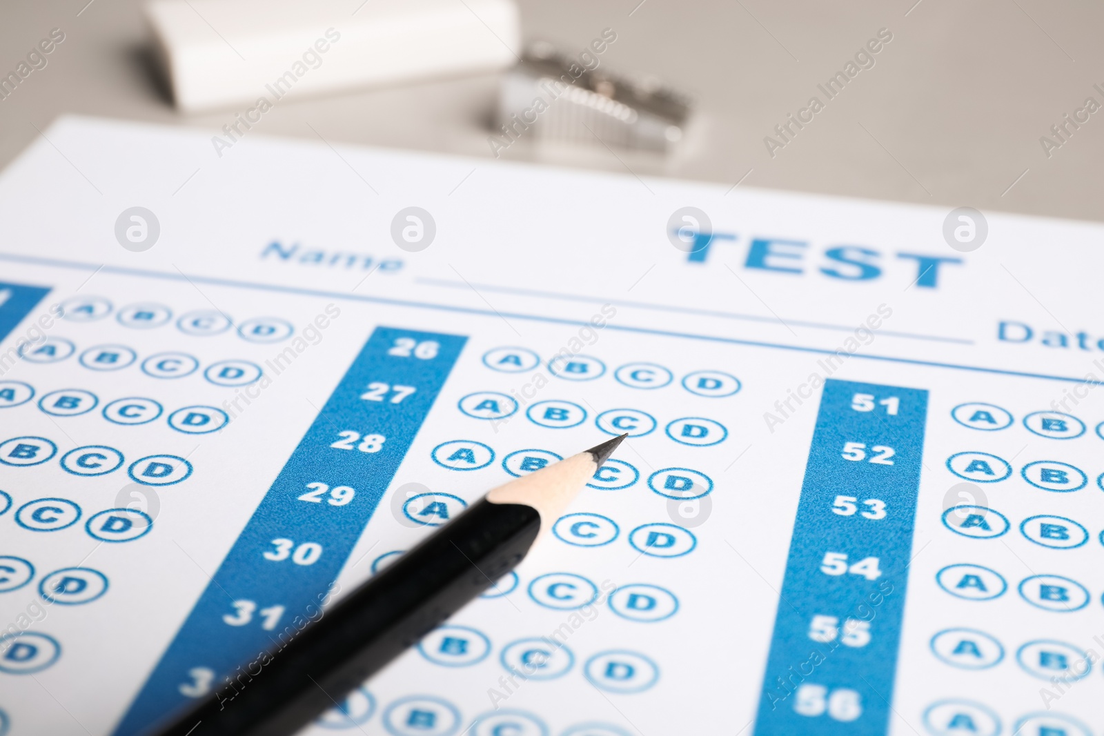 Photo of Answer sheet and pencil on light grey table, closeup. Student passing exam