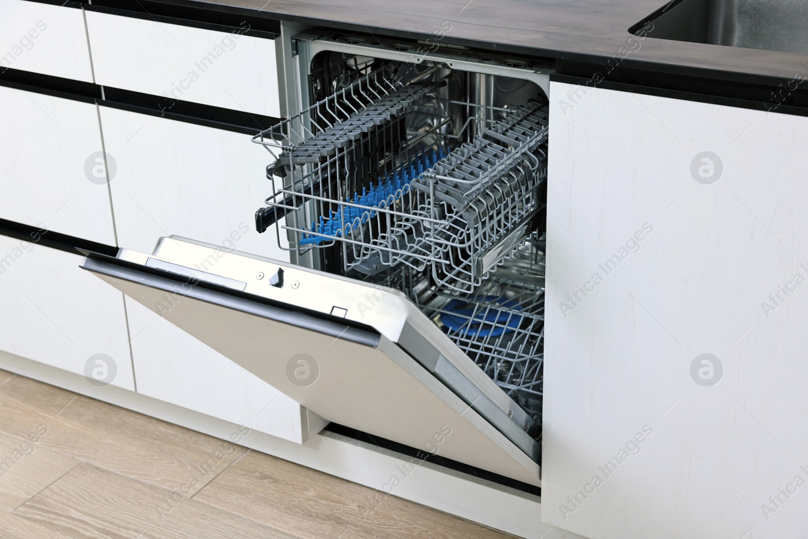 Photo of Built-in dishwasher with open door indoors. Home appliance