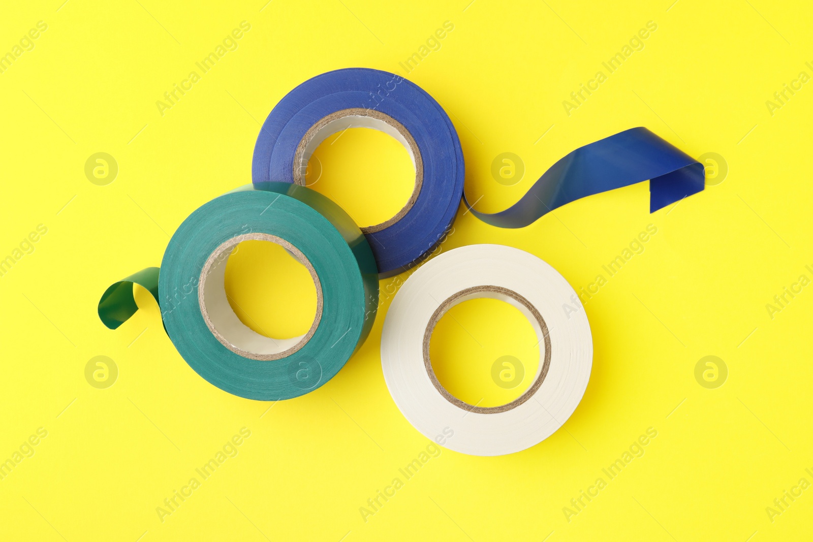 Photo of Colorful insulating tapes on yellow background, flat lay