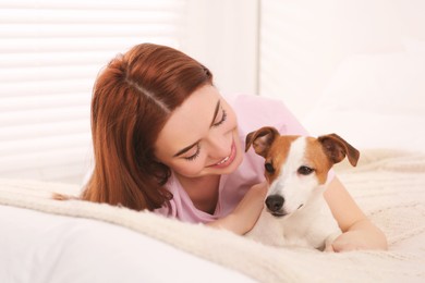 Woman with her cute Jack Russell Terrier dog on bed at home