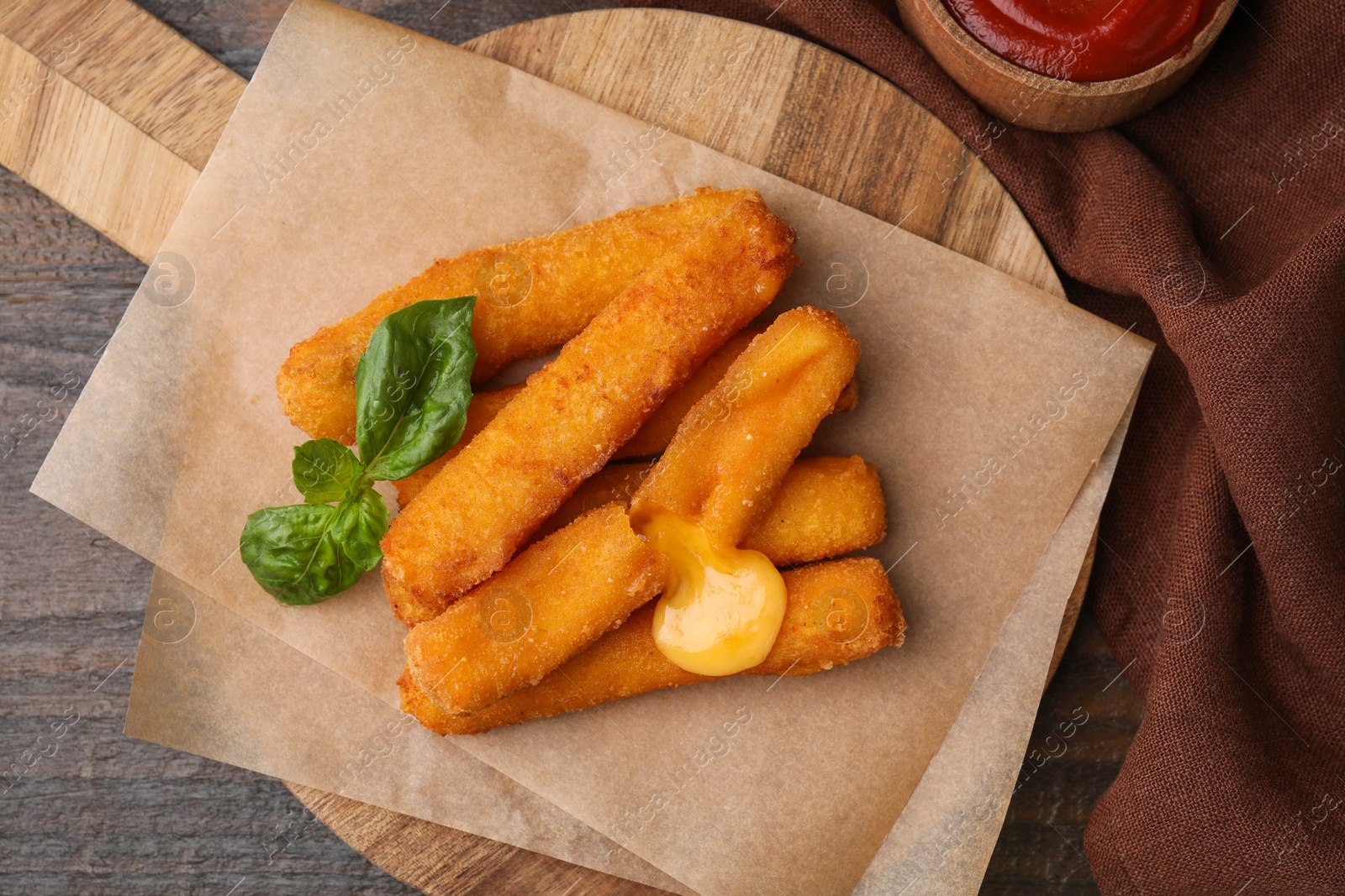 Photo of Tasty fried mozzarella sticks and basil on wooden table, flat lay