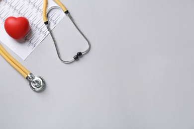 Photo of Stethoscope, cardiogram and red decorative heart on grey background, flat lay with space for text. Cardiology concept