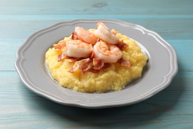 Photo of Plate with fresh tasty shrimps, bacon and grits on light blue wooden table