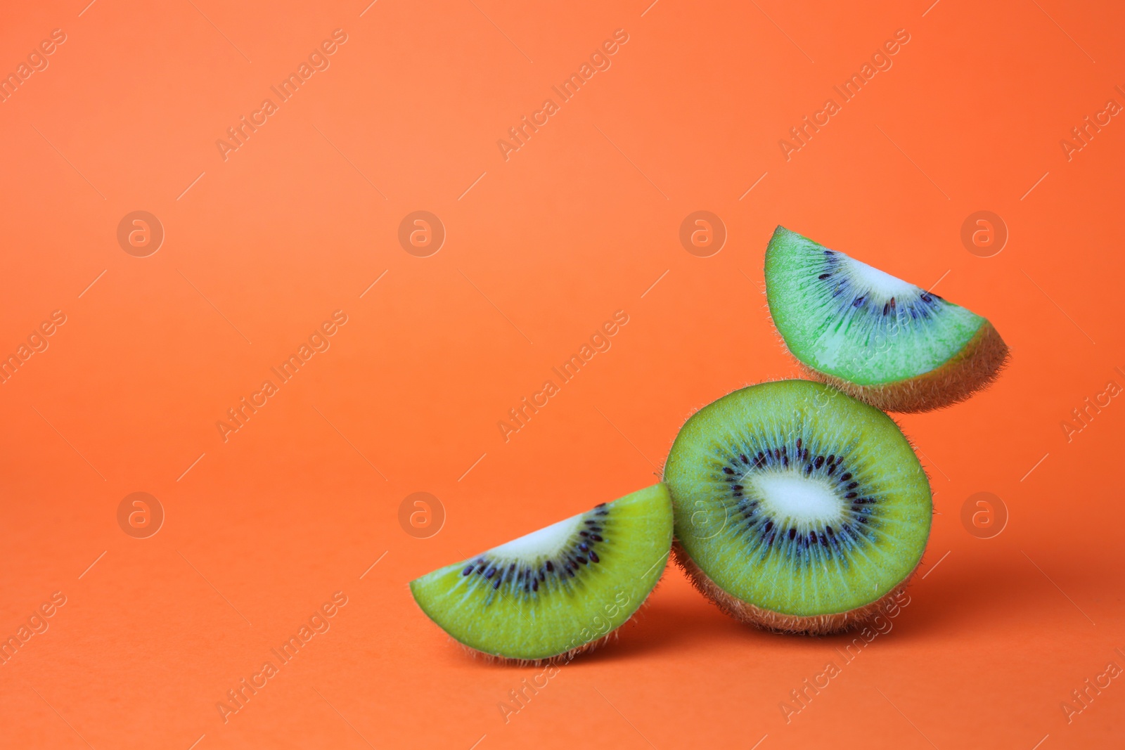 Photo of Cut fresh ripe kiwis on orange background, space for text