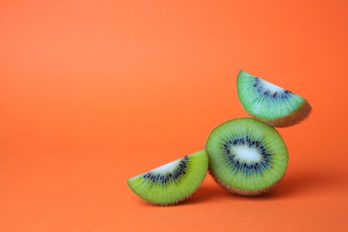 Cut fresh ripe kiwis on orange background, space for text