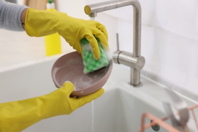 Photo of Woman washing plate above sink in modern kitchen, closeup. Space for text