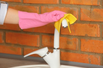Photo of Woman cleaning tap with rag, closeup view