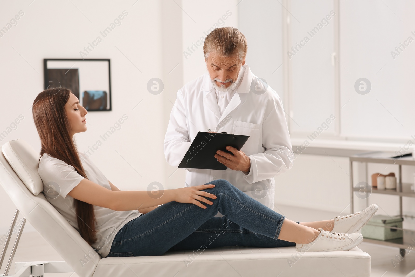 Photo of Orthopedist examining patient with injured knee in clinic