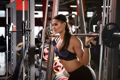 Young woman working out on Smith machine in modern gym
