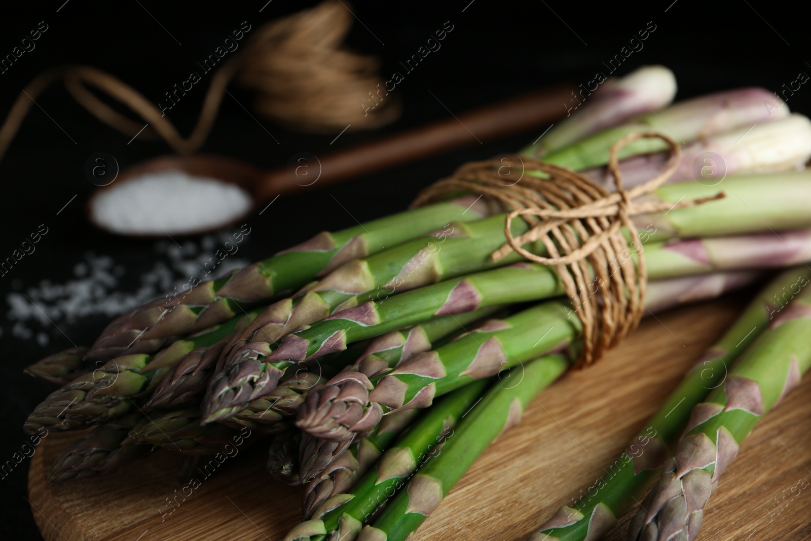 Photo of Raw green asparagus on wooden board, closeup