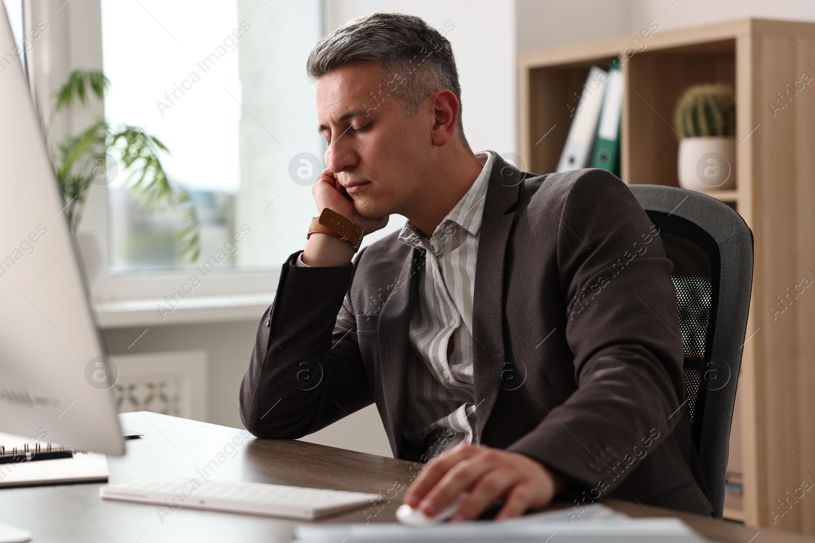 Photo of Man snoozing at wooden table in office