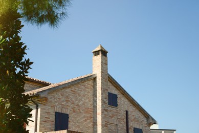 Photo of Beautiful view of brick cottage with chimney against blue sky