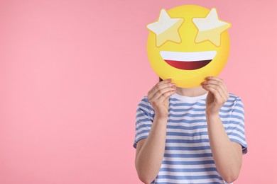 Photo of Woman holding emoticon with stars instead of eyes on pink background. Space for text
