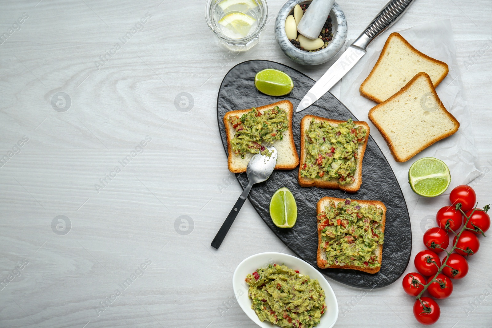 Photo of Delicious sandwiches with guacamole and ingredients on white wooden table, flat lay. Space for text