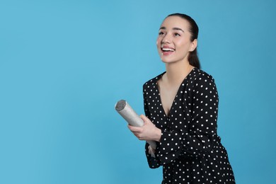 Photo of Young woman blowing up party popper on light blue background, space for text