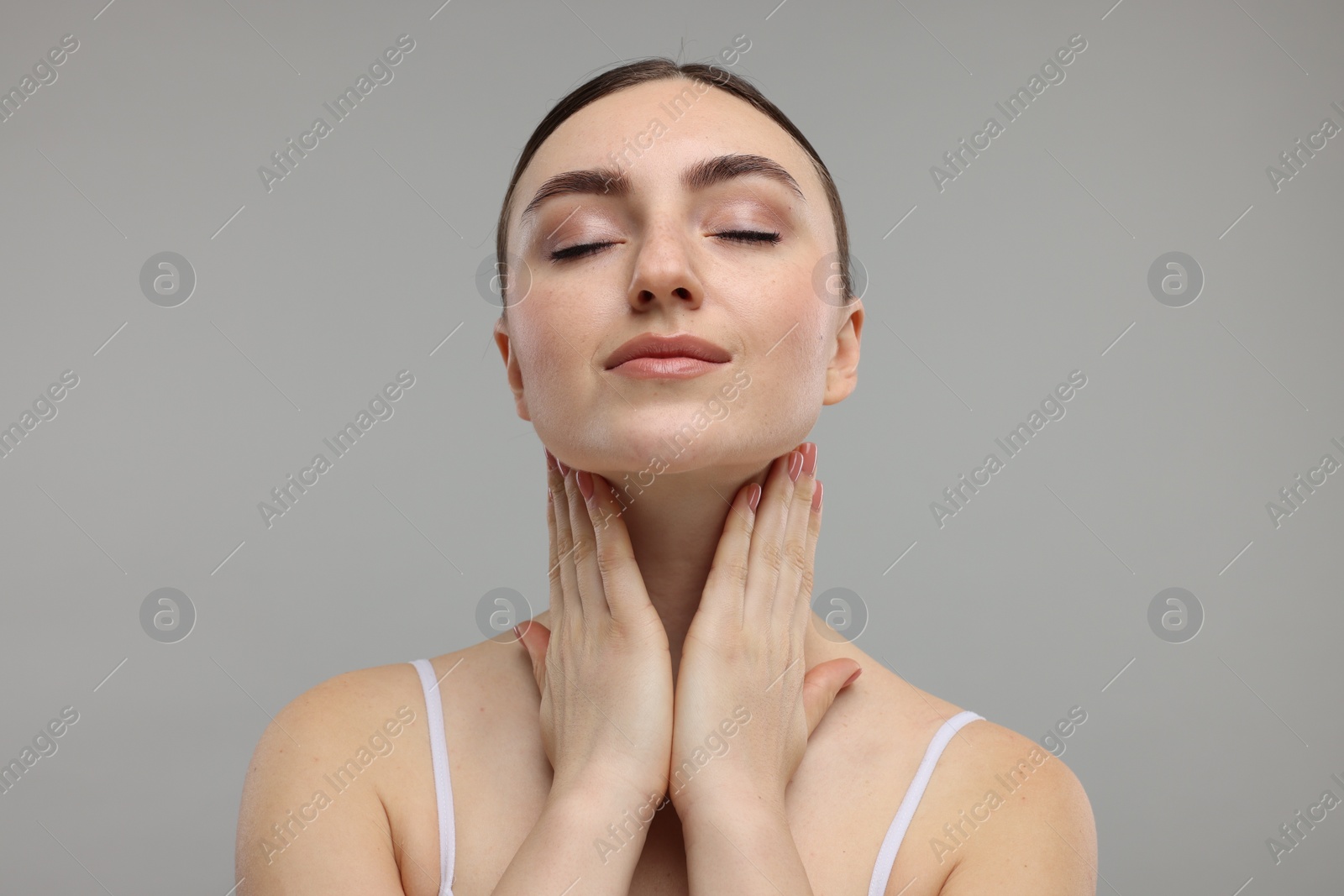 Photo of Beautiful woman touching her neck on grey background