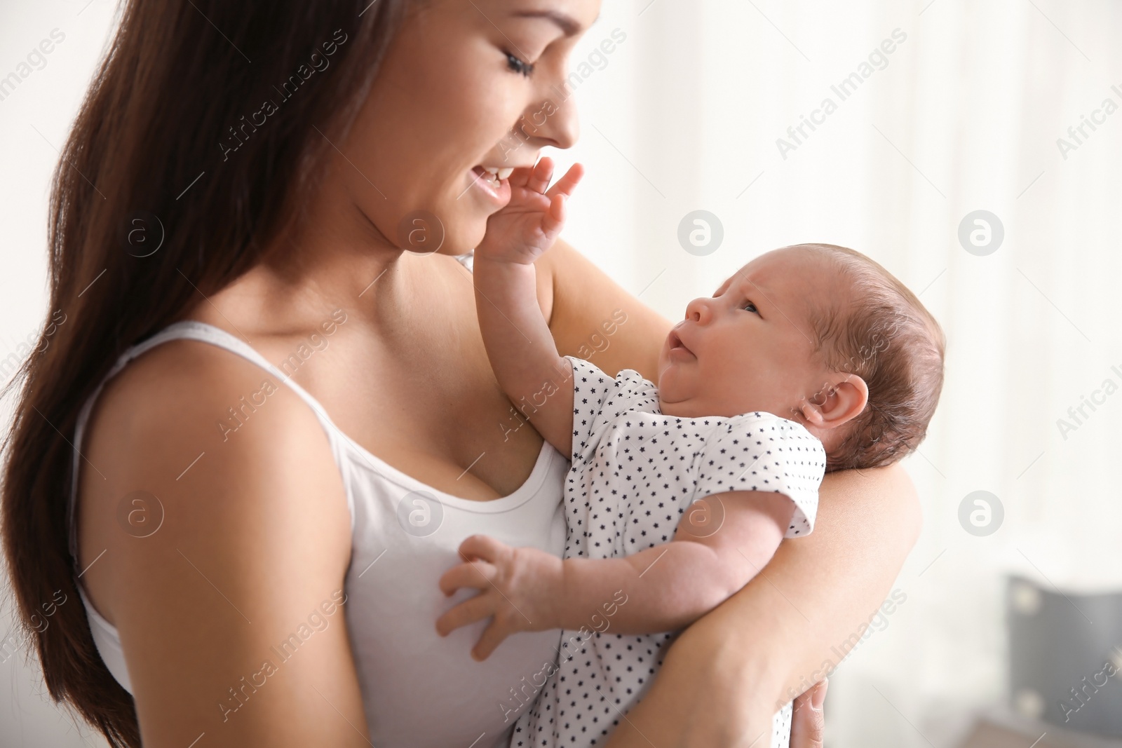 Photo of Young woman with her newborn baby on blurred background