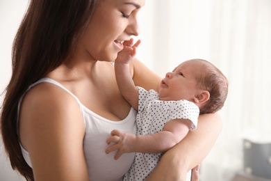 Young woman with her newborn baby on blurred background
