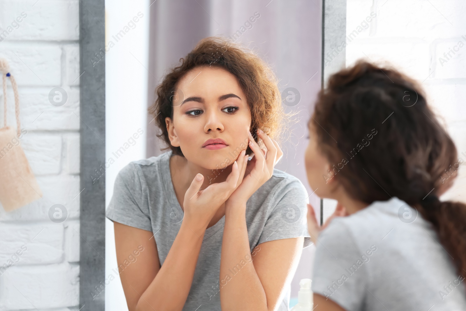 Photo of Beautiful young woman with acne problem looking in mirror at home