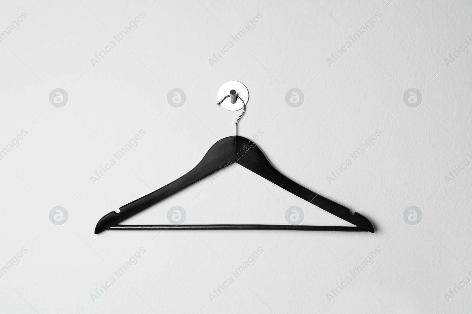 Photo of Empty black clothes hanger on white wall