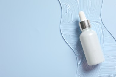 Bottle of cosmetic serum on light blue background, top view. Space for text