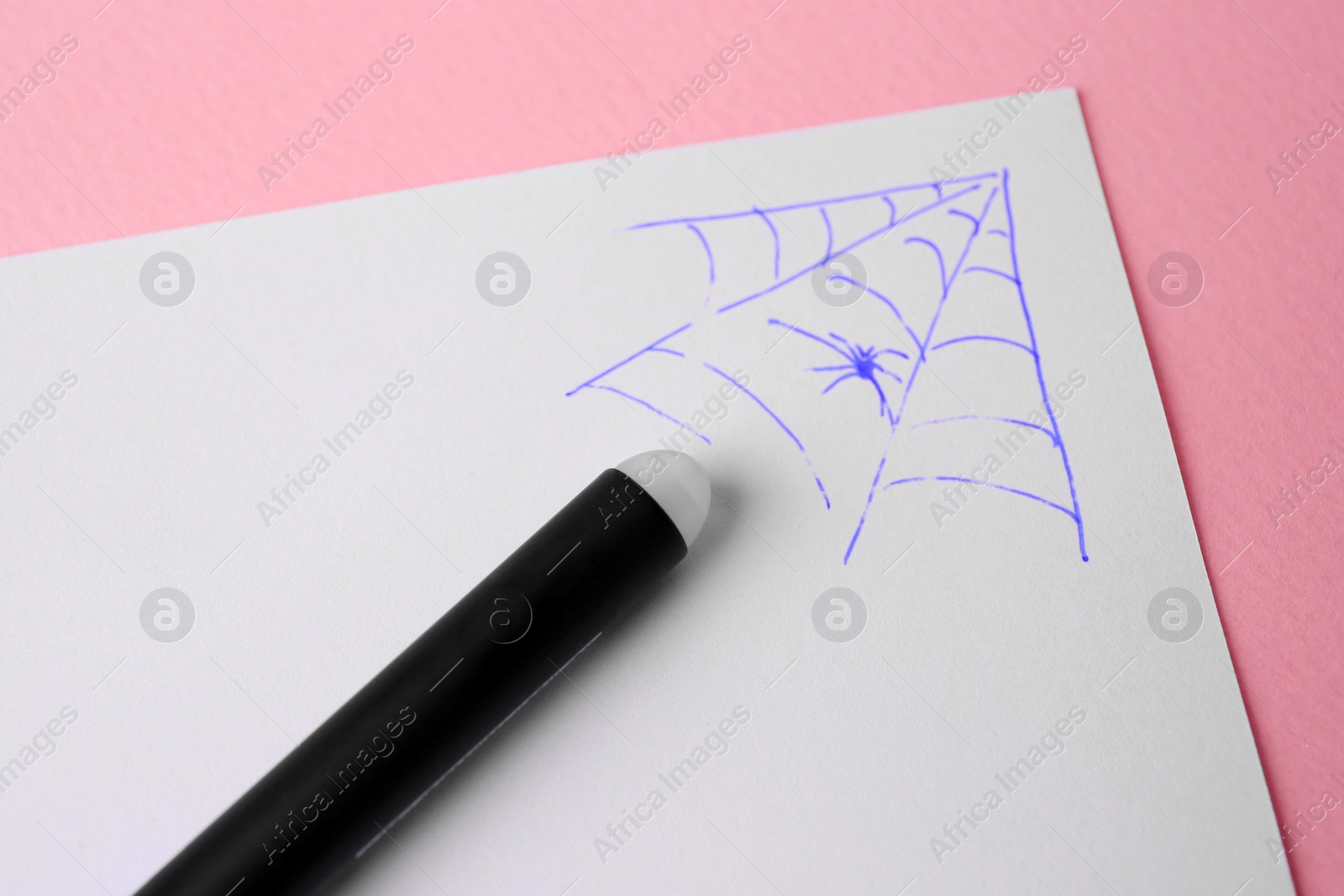 Photo of Web drawn on sheet of paper with erasable pen against pink background, closeup