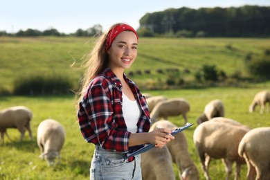 Photo of Smiling woman with clipboard on pasture at farm