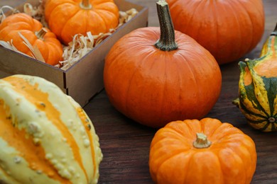 Crate and many different pumpkins on wooden table, closeup