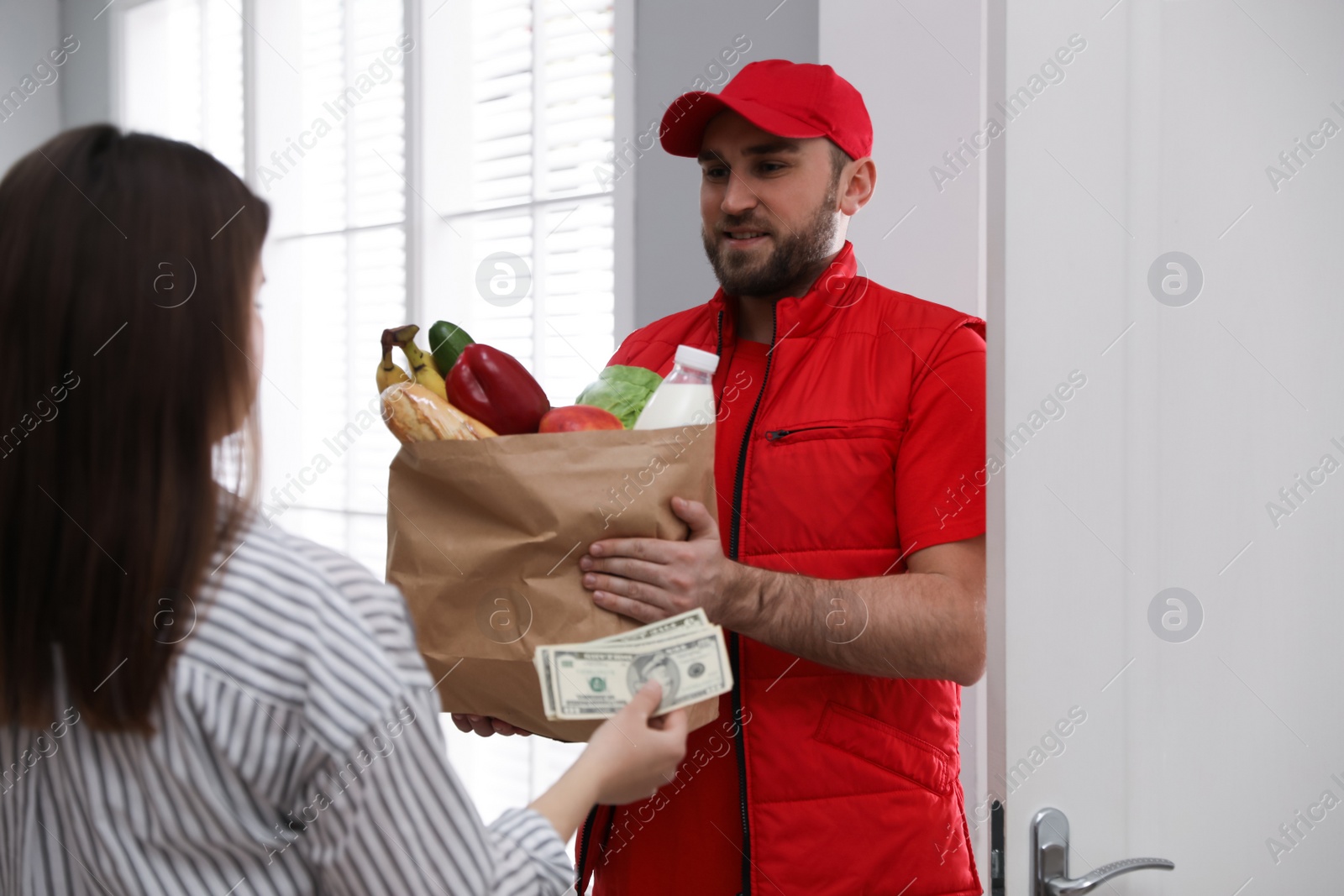 Photo of Young woman giving tips to courier indoors