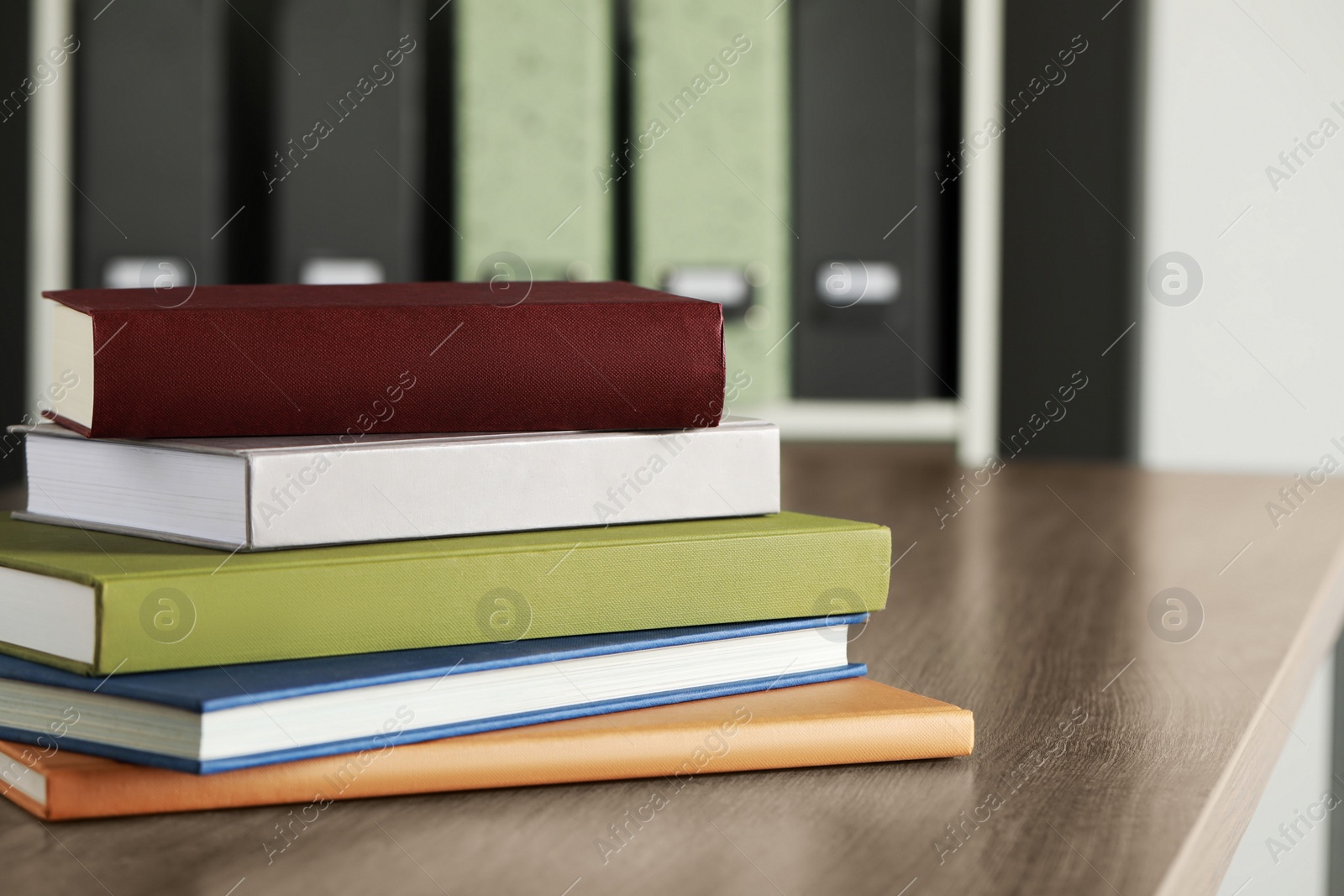 Photo of Many different books stacked on wooden table indoors, space for text