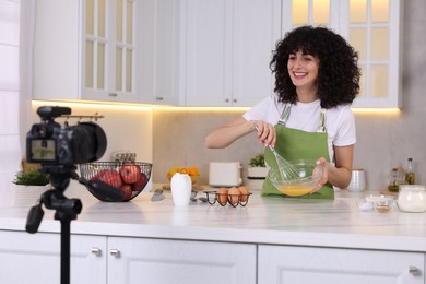 Photo of Smiling food blogger cooking while recording video in kitchen