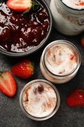 Photo of Tasty yoghurt with jam and strawberries on grey textured table, top view