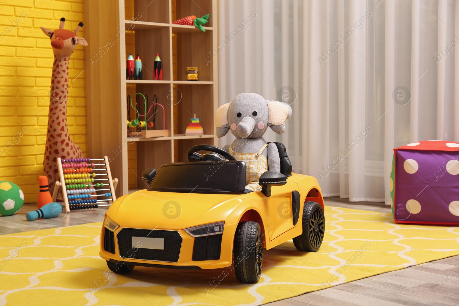 Photo of Child's electric car with toy elephant in playroom