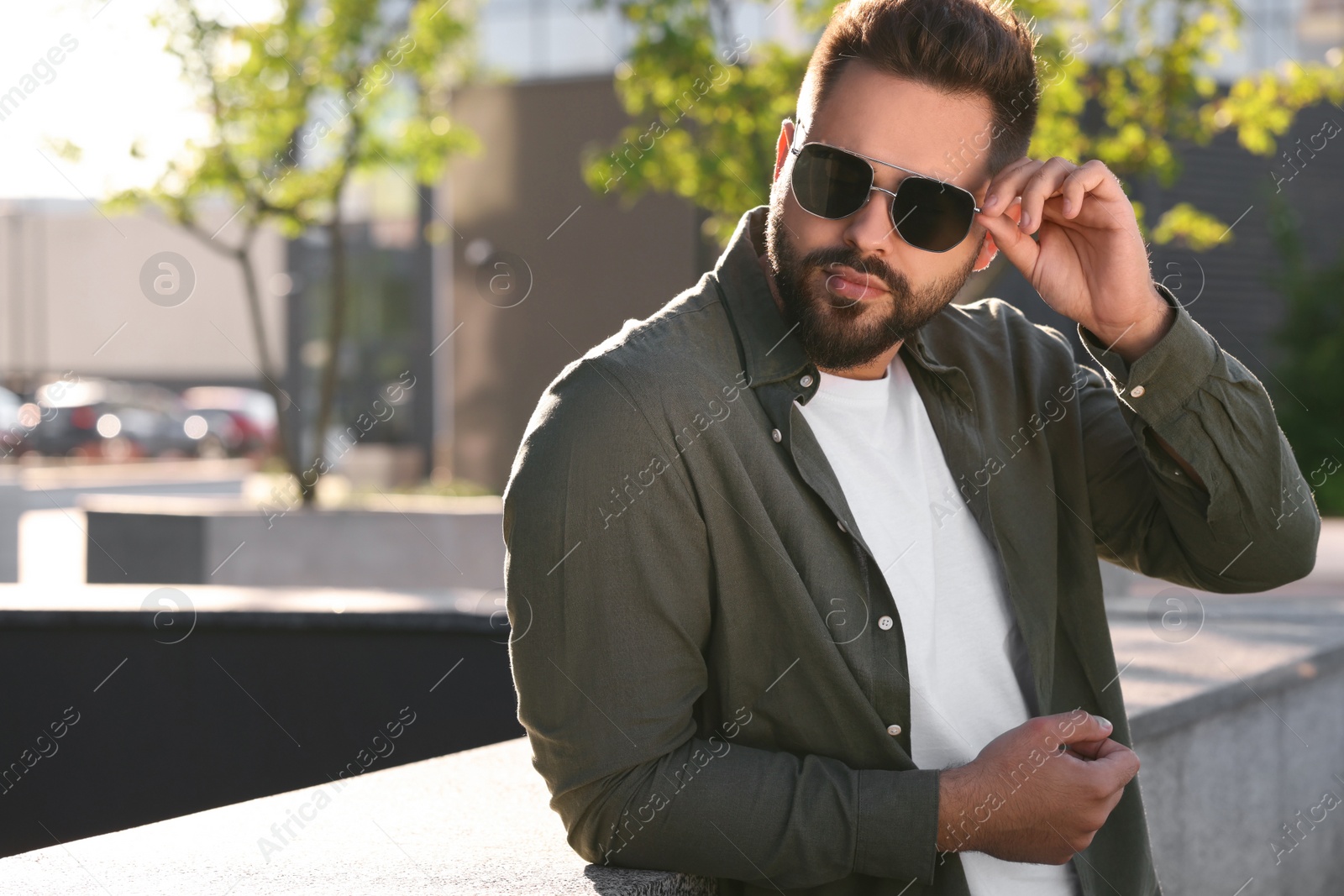 Photo of Handsome young man in sunglasses on city street, space for text