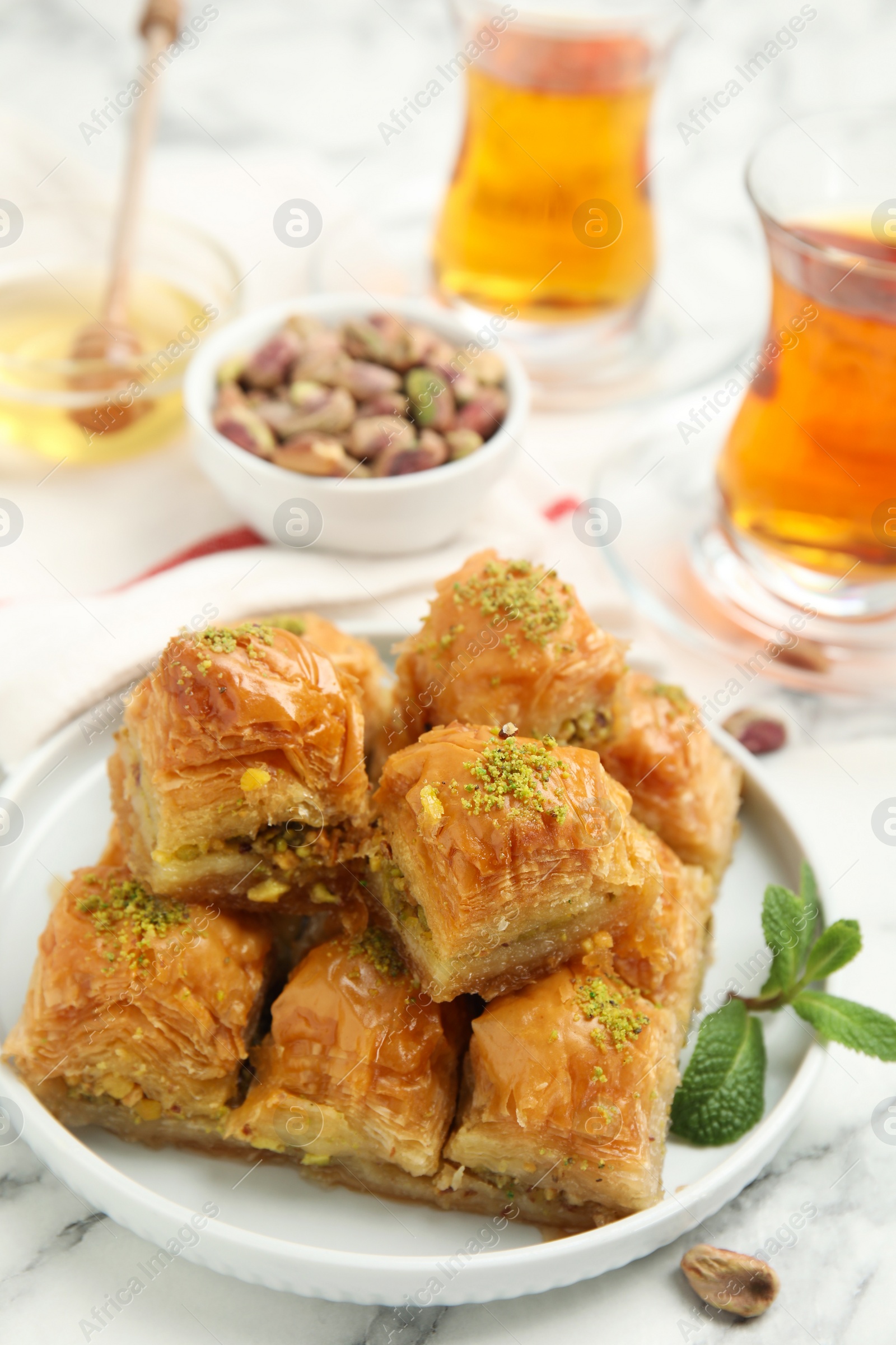 Photo of Delicious sweet baklava with mint on white marble table