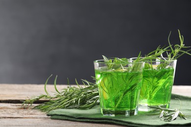 Photo of Glasses of refreshing tarragon drink on wooden table. Space for text