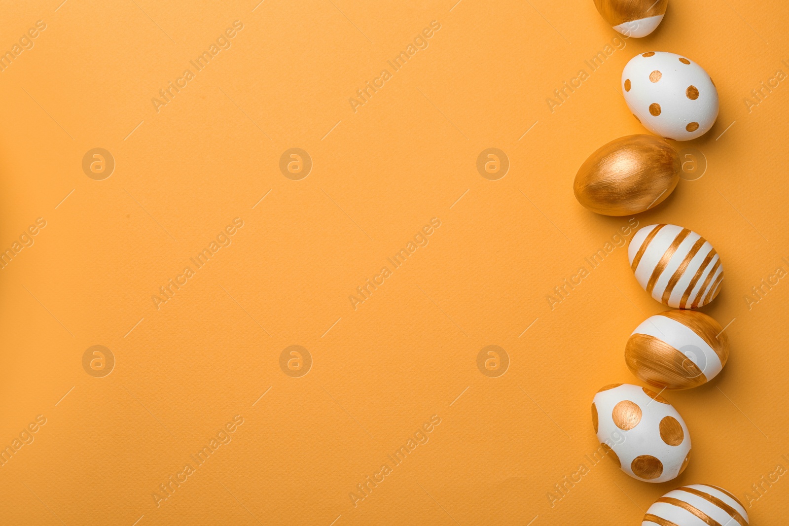 Photo of Set of traditional Easter eggs decorated with golden paint on color background, top view. Space for text