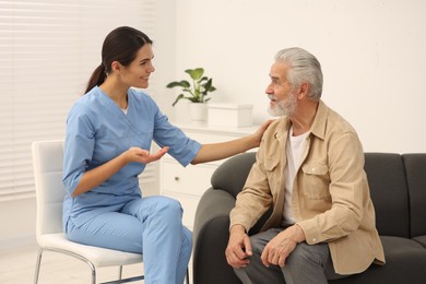 Photo of Health care and support. Nurse talking with elderly patient in hospital