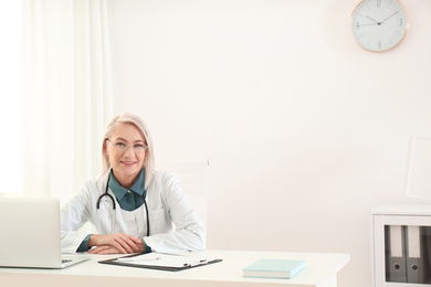 Portrait of mature female doctor in white coat at workplace