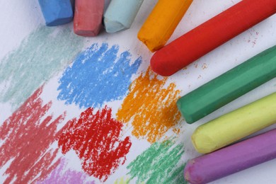 Photo of Colorful pastel chalks and scribbles on white background, flat lay. Drawing materials