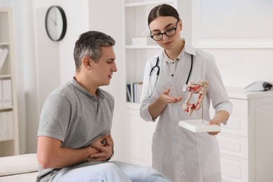 Photo of Gastroenterologist with anatomical model of large intestine consulting patient in clinic