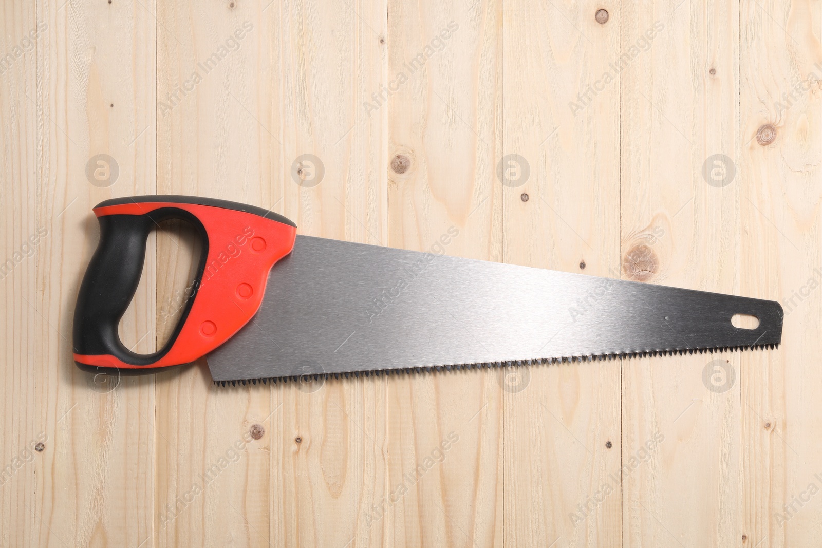 Photo of Saw with colorful handle on wooden background, top view