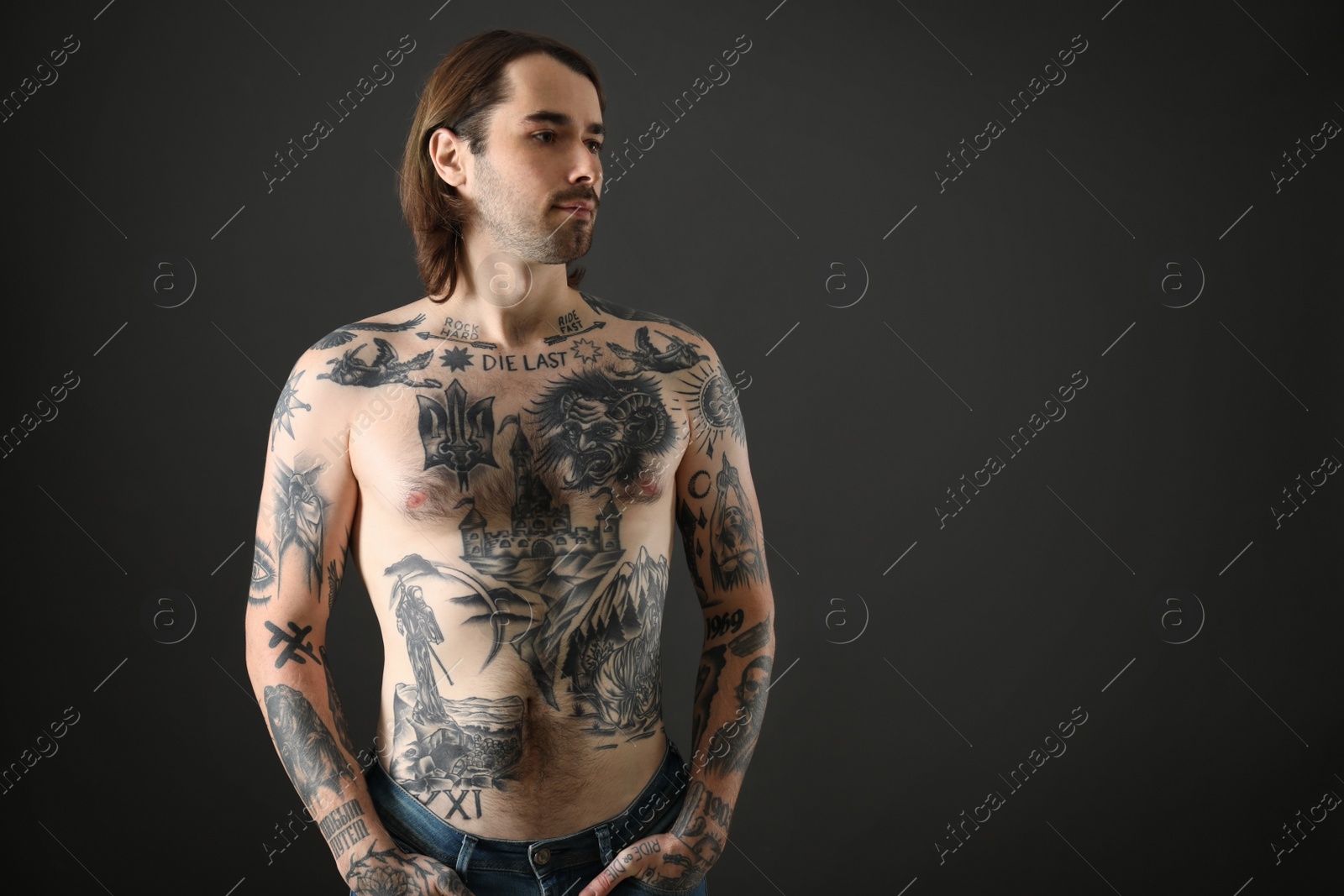 Photo of Young man with tattoos on body against black background. Space for text