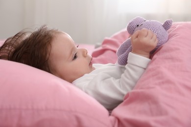 Photo of Cute little baby with toy on bed indoors