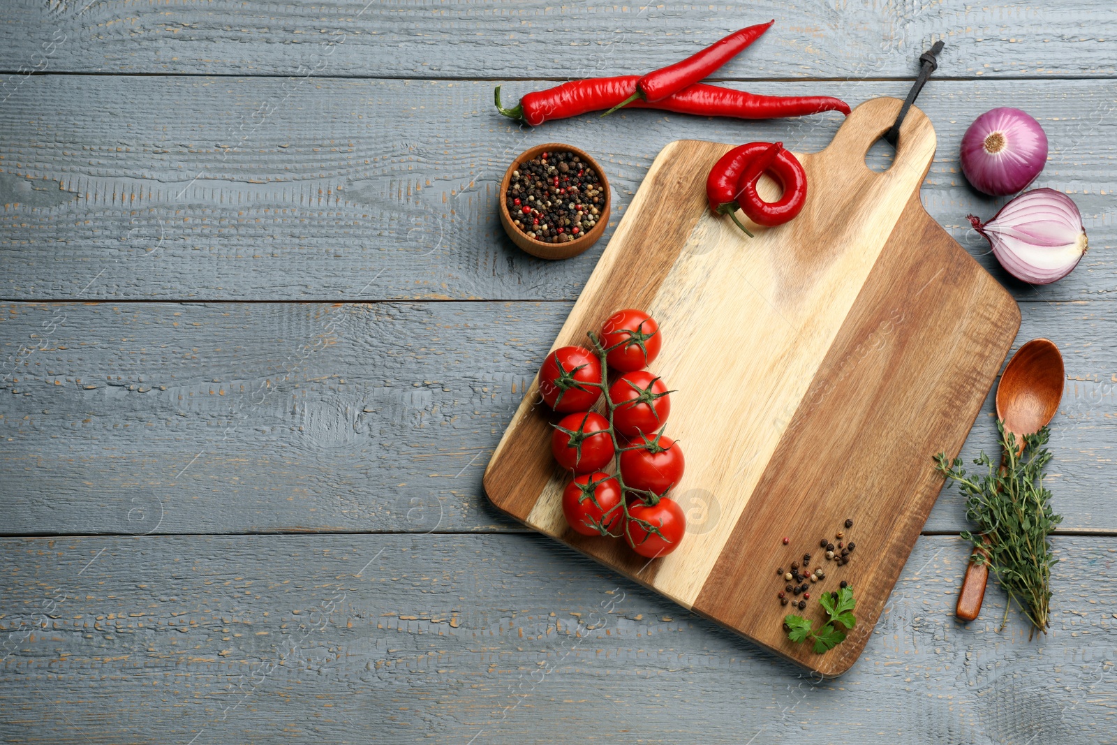 Photo of Cutting board and vegetables on grey wooden table, flat lay with space for text. Cooking utensil